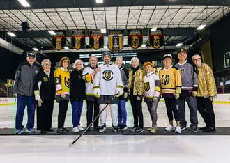 seniors posing with professional hockey player in the middle of the ice rink