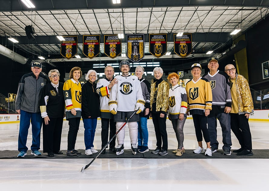seniors posing with professional hockey player in the middle of the ice rink
