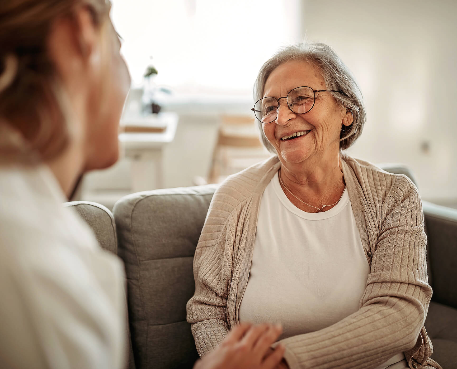 elderly lady sitting on the couch talking to another person
