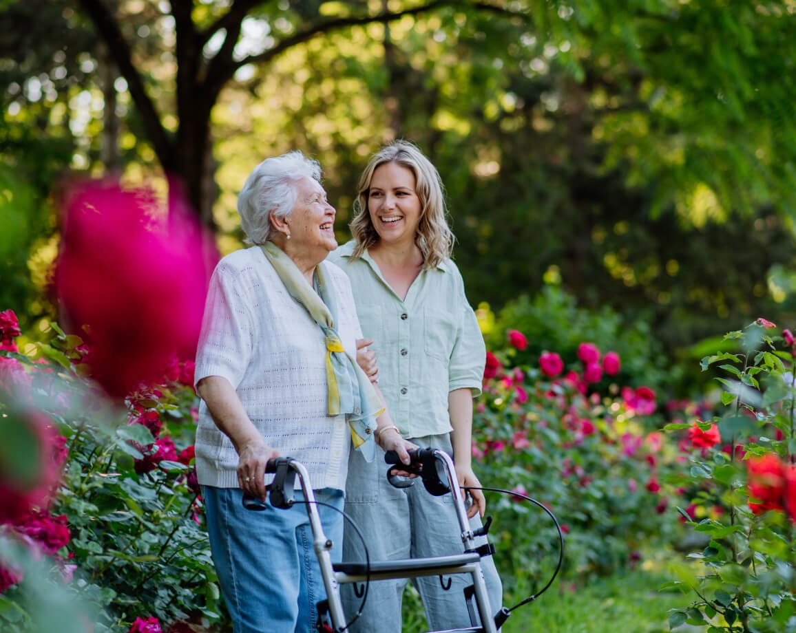 Senior woman using a walker while walking with her adult daughter