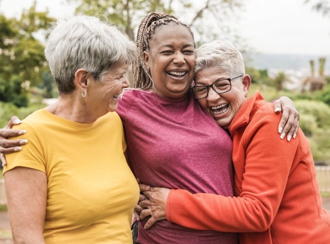 Three senior women outside hugging