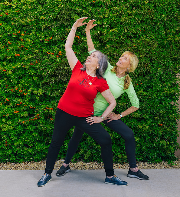 senior with exercise coach doing stretches outside